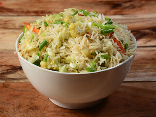 Healthy and tasty veg fried rice made of mixed veggies served in bowl over a rustic wooden background, Indo chinese, Indian cuisine, selective focus