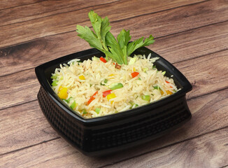 Healthy and tasty veg fried rice made of mixed veggies served in bowl over a rustic wooden background, Indo chinese, Indian cuisine, selective focus