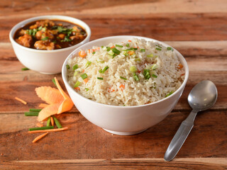 Healthy and tasty veg fried rice and gobi manchurian dry with tomato sauce served in bowl over a rustic wooden background, Indian cuisine, selective focus
