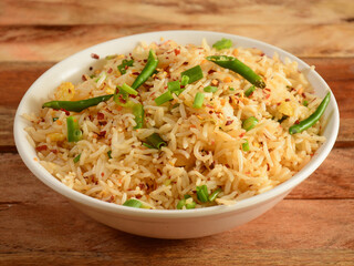 Healthy and tasty Malaysian veg fried rice served in bowl over a rustic wooden background, selective focus