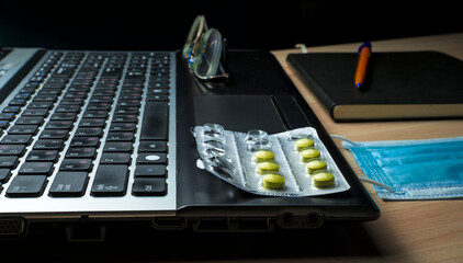 Laptop with pills and medical mask