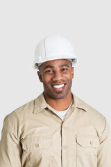 Portrait of happy young African male construction worker over gray background