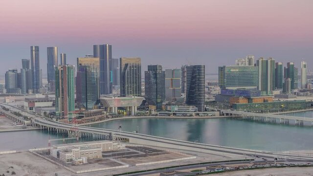 Aerial skyline of Abu Dhabi city centre from above day to night transition timelapse after sunset with illuminated skyscrapers.
