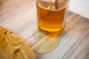 Honey jar and a slice of bread with peanut butter on wooden table