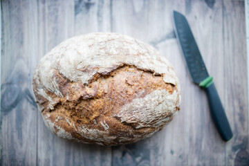 Sourdough bread and a knife on a wooden table from above