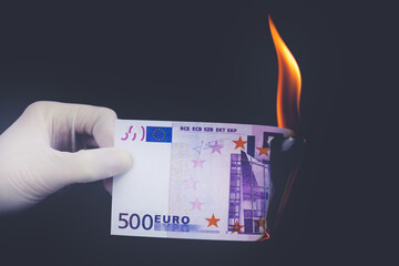 A five hundred euro bill is burning on a black background. Bankruptcy concept.