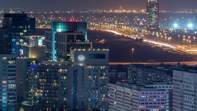Aerial skyline of Abu Dhabi city centre from above night timelapse with illuminated skyscrapers with traffic on road