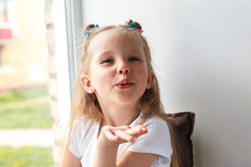 portrait of cute little girl sending an air kiss at home