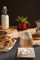 iced latte coffee served with whipped cream topping and chocolate syrup in wine glass place on wooden table