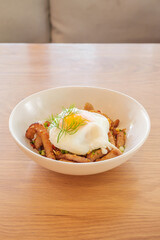 Poached Egg with Grilled Pork Neck rice in white plate on wooden table at restaurant.