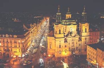 Naklejka premium Aerial view of Old Town square with illuminated St. Nicholas' Church, a hussite place of worship built in the 12 century in Prague, Czechia.