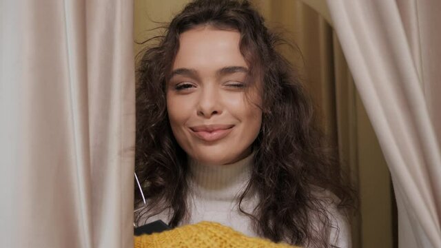 Cheerful face of a beautiful girl in a fitting room of a stylish boutique. Young woman smiling and posing for the camera in a clothing store.