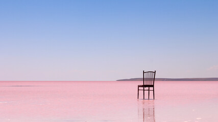 Fototapeta na wymiar A chair with no people on the pink water of salt lake in front of a minimalist background