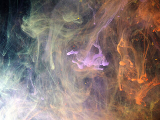 Dissolving paint drops of different colors in water. Red, blue, green, black, purple paint stains in the water.