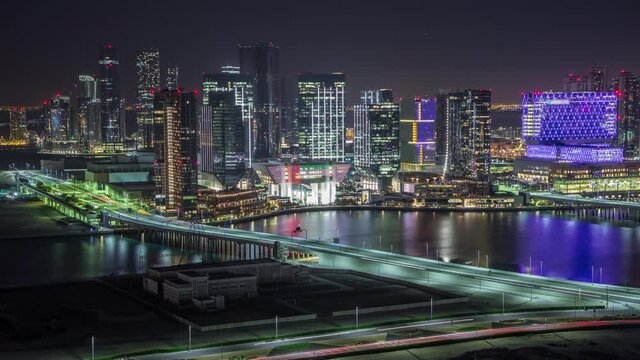 Aerial skyline of Abu Dhabi city centre from above night timelapse with illuminated skyscrapers with bridge and traffic on a road
