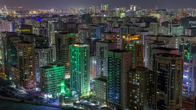 Aerial skyline of Abu Dhabi city centre from above night timelapse with illuminated skyscrapers.