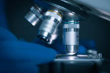 Fototapeta na wymiar Close-up shot of sample slide and microscope with metal lens at laboratory.