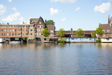 Summery panoramic view of the Amstel river in the South of Amsterdam. Modern highrise MessageBird and houseboats.