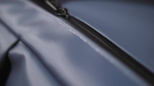 Close-up of travel backpack. Hands close suitcase. Person check quality of goods. Macro shot of unzipping and zipping bag.