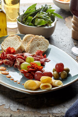 summer picnic with wine and snacks. Flat-lay of charcuterie and cheese board, rose wine, nuts, olives and fruits over wood table background
