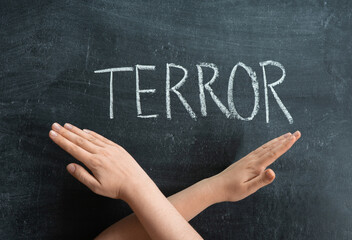 The inscription TERROR on a chalkboard, crossed female hands on the background of the text
