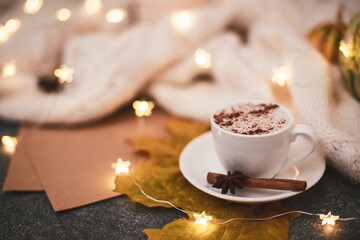 A cup of hot cappuccino, brown paper, knitted blanket, garland. Copy space.