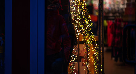 Blur of lighting in night street background. Selective focus. Christmas lights in the dark. Image of blurred background with warm colorful lights. Shopping, winter holidays.
