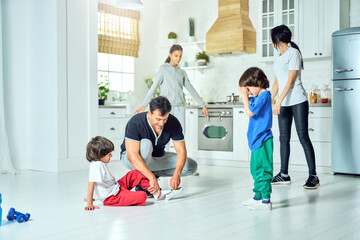 Energize your day. Loving hispanic father putting on shoes on his little son while getting ready for family workout in the morning at home. Healthy lifestyle