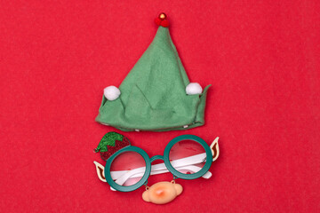 Elf hat and glasses, accessories for Christmas celebration on red background