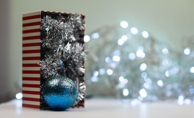 a small box with Christmas decorations for the Christmas tree on a background of bokeh of lights garlands