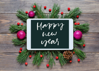 Christmas or new year background on a wooden background. Happy New year-handwritten inscription on the gadget screen