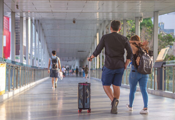 Rear view of tourist couple holding hands and dragging luggage, sightseeing visiting street, outdoors