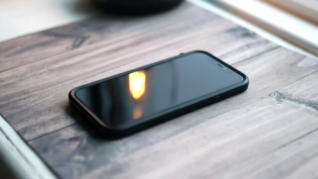 Screen of black iPhone 11 showing on wooden table