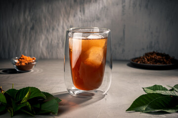 Black tea with tea tree leaves in a double-walled glass Cup
