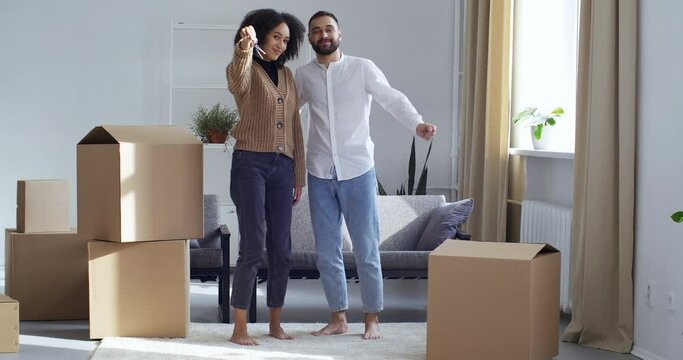 Couple African American Mixed Race Black Woman Girlfriend And Caucasian White Male Husband Boyfriend Stand In Living Room In New House Next To Cardboard Boxes Show Bunch Of Keys, Apartment Purchase