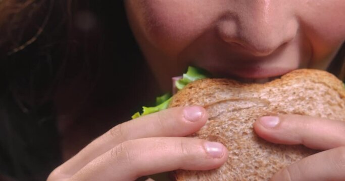 Young woman holding and eating sandwich