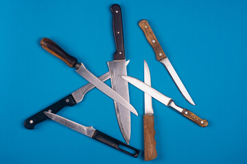Several old kitchen knives on the table. View from above.