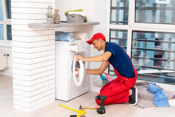 male adult repairman with tool and clipboard checking washing machine in bathroom