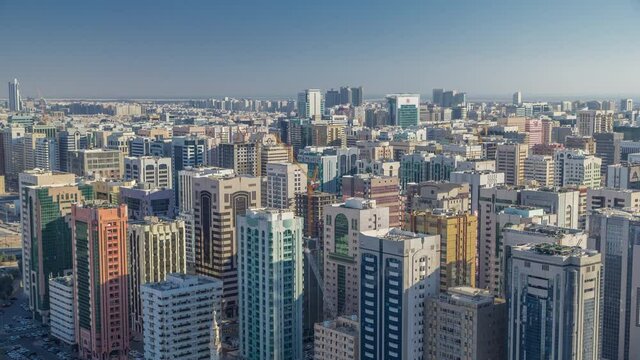 Aerial skyline of Abu Dhabi city centre with many towers from above timelapse before sunset with shadows from skyscrapers