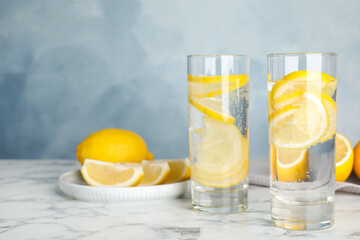 Soda water with lemon slices on white marble table. Space for text