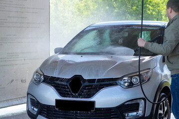 Fototapeta na wymiar Car wash on a contactless car wash. A man washes the car. Put the car in order