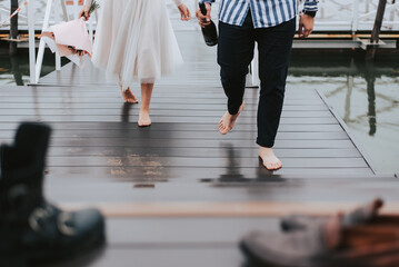 Obraz premium Feet of the newlyweds on the background of the pier.The bride and groom go barefoot along the wharf.