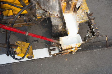 Obraz premium The machines are pouring white paint over the road to divide the lines on the road.
