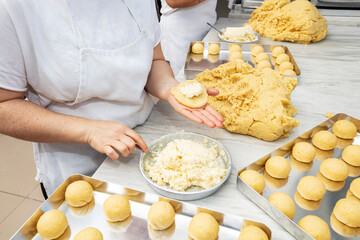 Producing classic croissants at the bakery shop. Woman is rolling dough into rolls for further baking. French pastry goods.