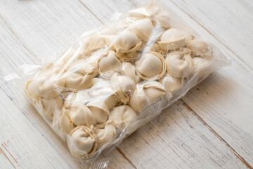 frozen dumplings in packaging on a white wooden background.