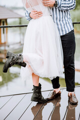 Legs of the newlyweds on the background of the pier.The bride and groom stand and pose in shoes on the wharf.