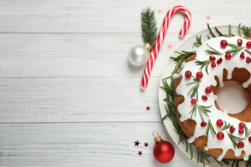 Flat lay composition with traditional Christmas cake and decorations on white wooden table, space for text