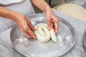Producing classic croissants at the bakery shop. Woman is rolling dough into rolls for further...