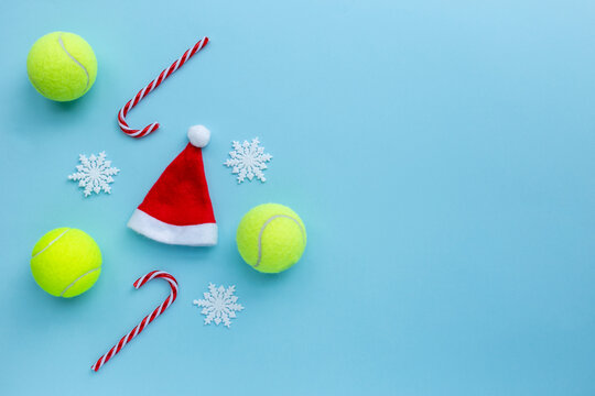 Santa hat , tennis balls , candy canes and snow flakes on blue background. Merry Christmas and New year concept with tennis balls. sport lifestyle. Flat lay, flatlay, copy space.