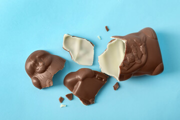 Broken chocolate Santa Claus on light blue background, flat lay